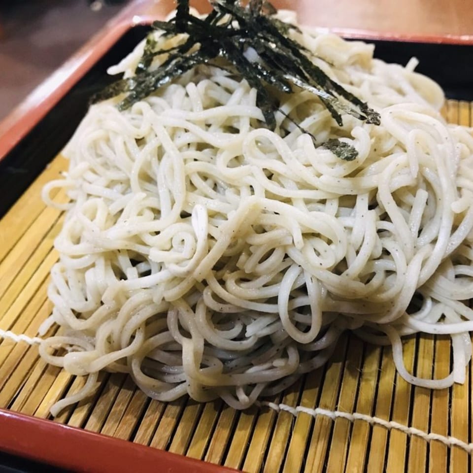 Japanese soba noodles topped with nori seaweed, served on a bamboo mat at Inakaya.